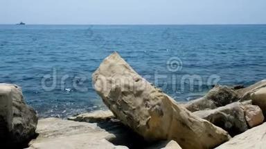 在晴朗的日子里特写一片石滩。 海滩上的岩石和鹅卵石，淹没了<strong>浪花</strong>和海浪。